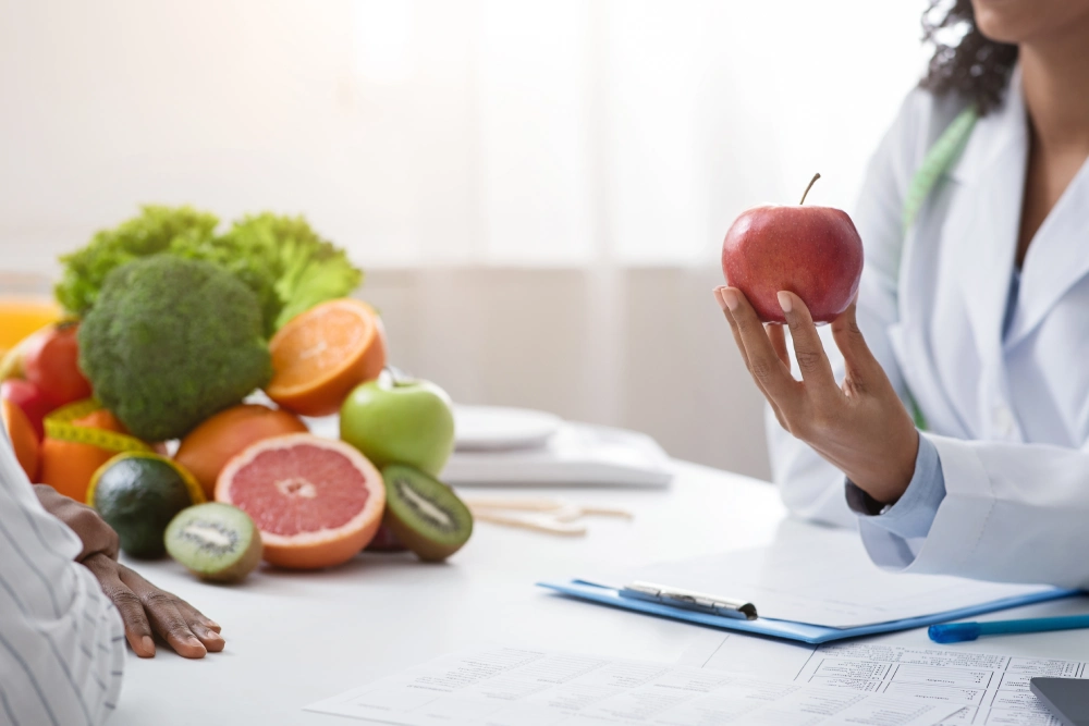 A person holding an apple in front of some fruits